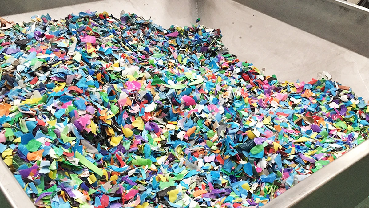 Mixed colored plastic flakes in a stainless steel hopper
