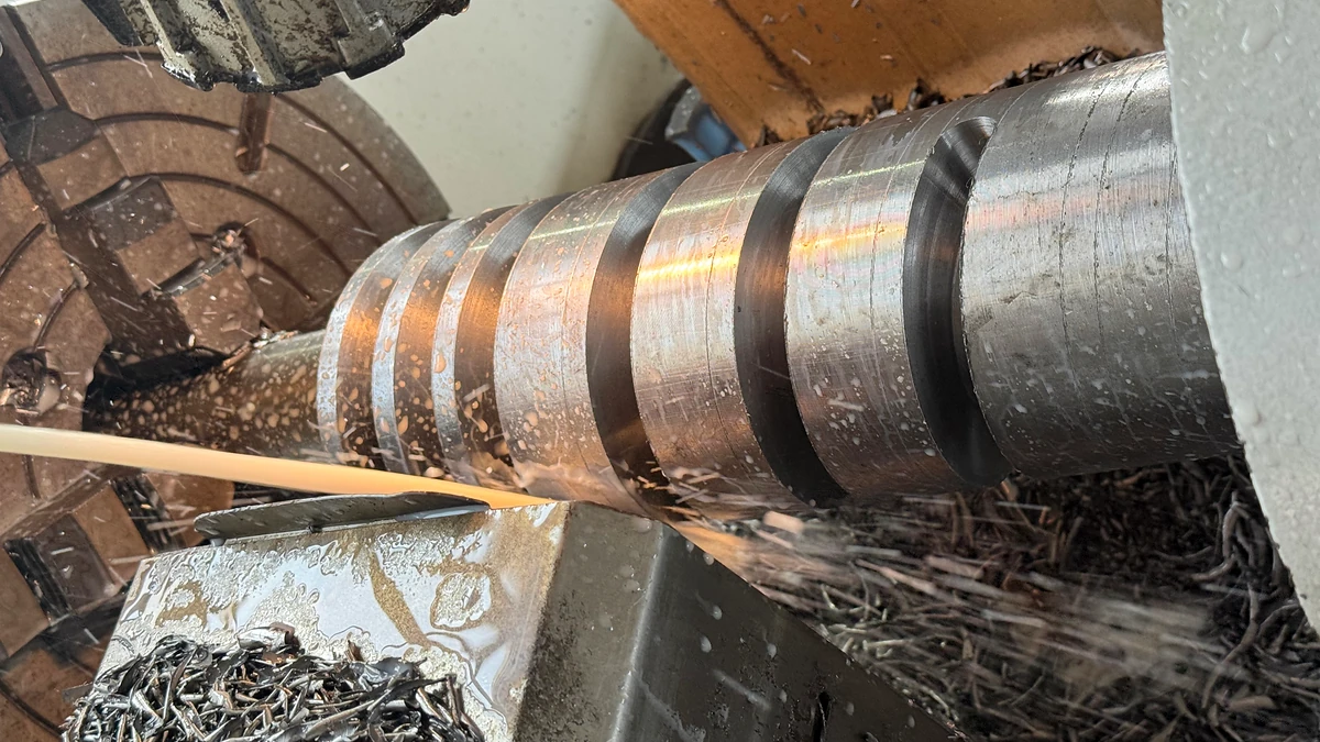 Close view of a screw workpiece during machining with metal chips and cutting fluid