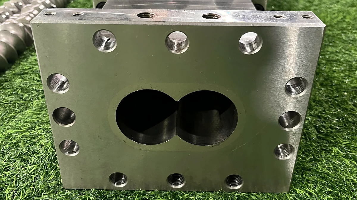 Machined modular barrel face showing intersecting bores and surrounding bolt holes.