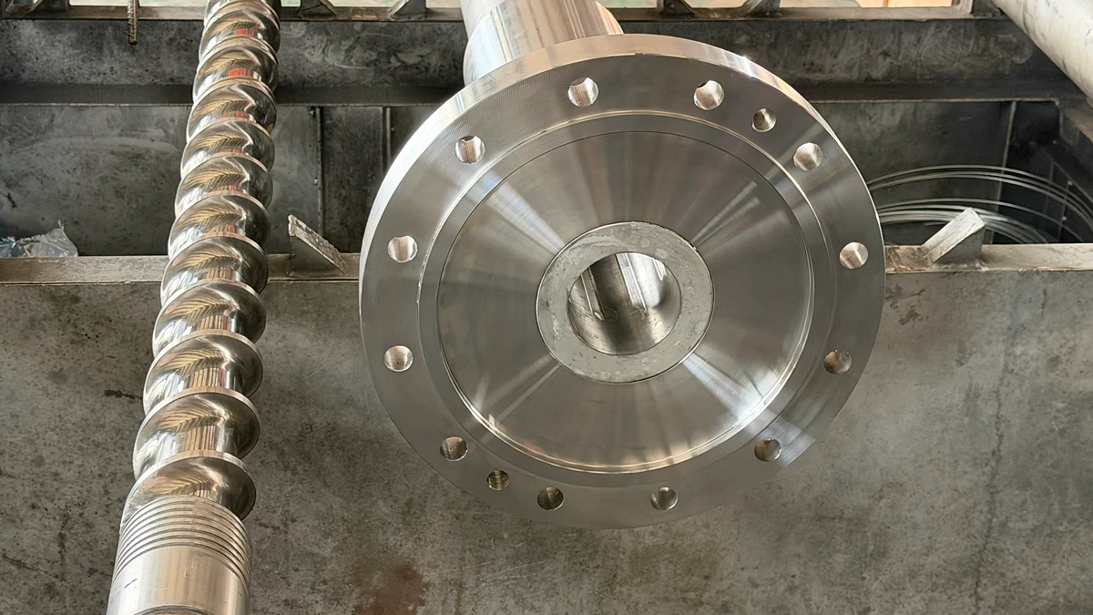 Circular barrel bore and bolt-hole flange beside a polished extruder screw.