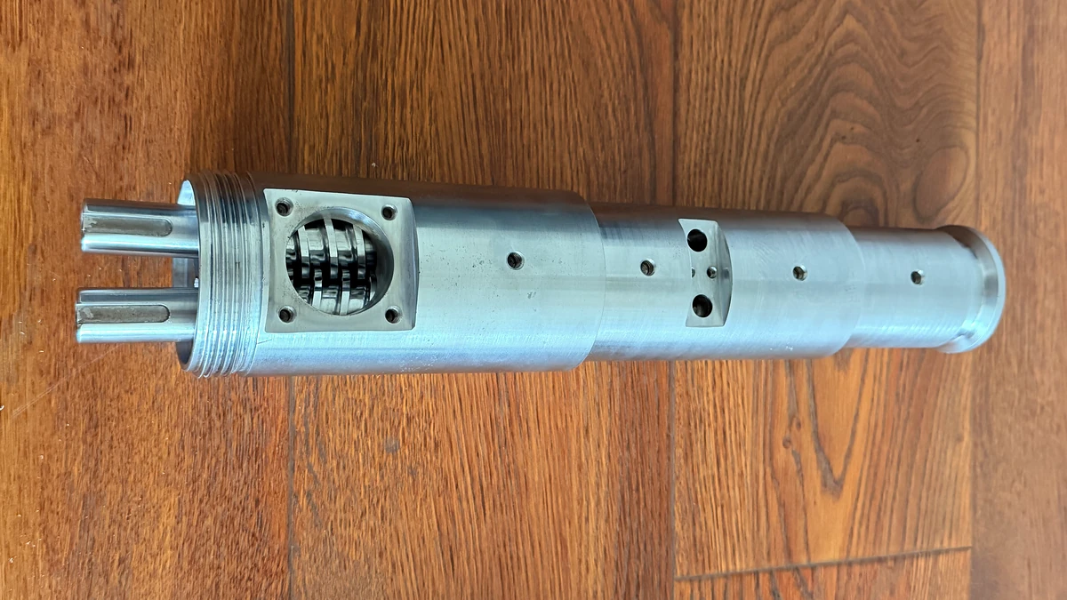 Small twin-screw barrel assembly showing its feed opening and protruding screw ends.