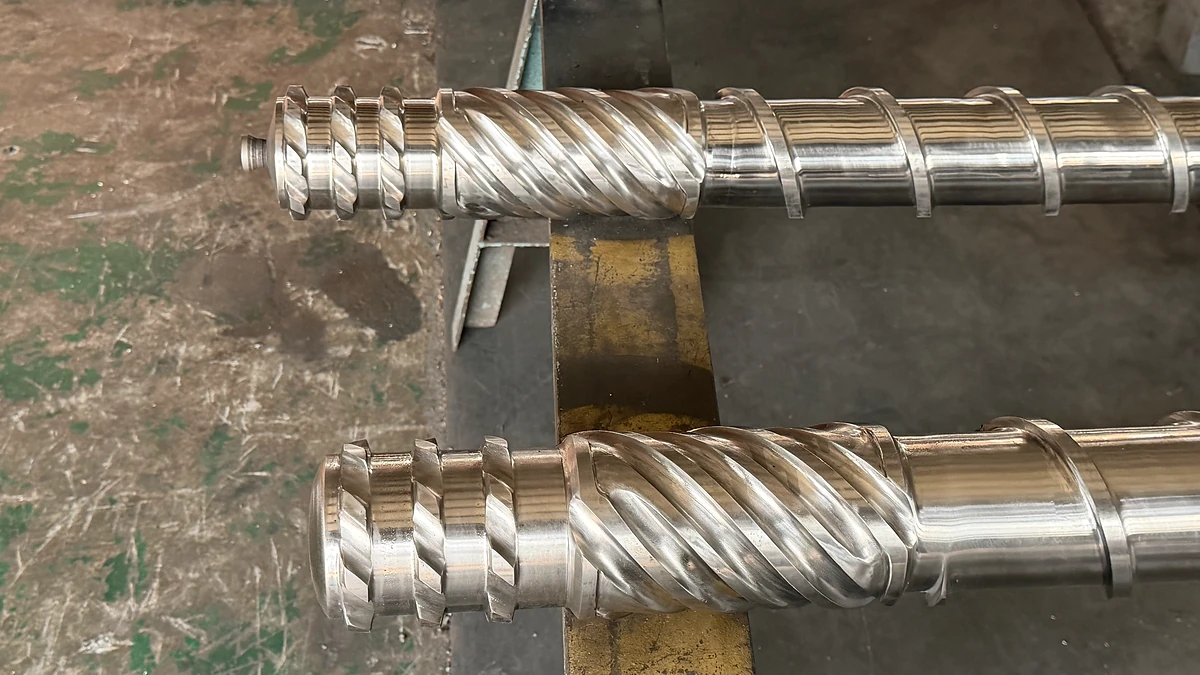 Two polished extruder screw end sections with different flight profiles.